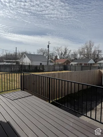 Elevated deck featuring composite decking and a black metal railing, overlooking a fenced backyard
