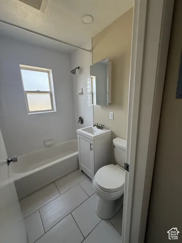 Bathroom featuring a white subway tile shower surround, porcelain floor tile, single-basin vanity cabinet, and wall-mounted medicine cabinet