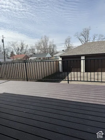 Composite deck featuring a black metal railing, wood-tone privacy fencing, and a detached two-car garage