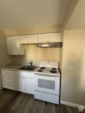 Kitchenette featuring white cabinetry, stone-finish countertops, stainless steel range hood, built-in electric range, and wood-finish flooring
