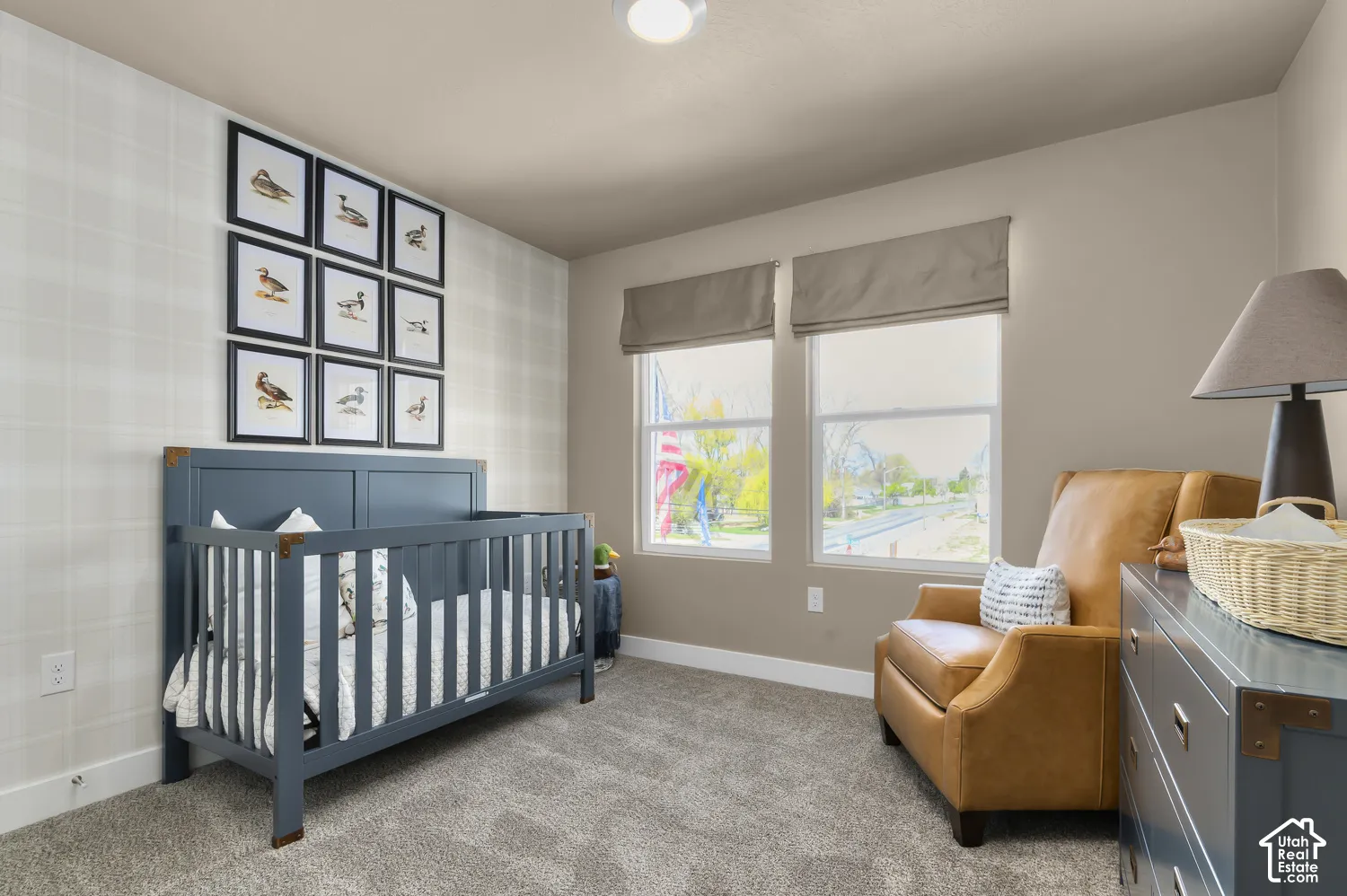 Neutral-toned room featuring a soft-patterned accent wall, high-pile carpeting, and two windows with integrated fabric shades