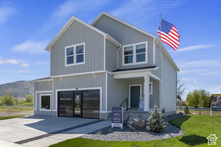 Two-story exterior featuring board-and-batten siding, a covered entryway, concrete driveway, and mountain backdrop