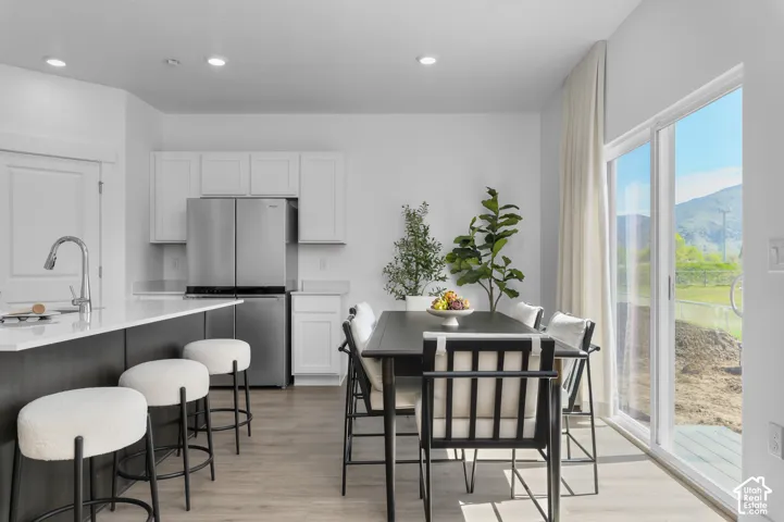 Kitchen featuring white cabinetry, a center island with a stone-finish countertop, stainless steel refrigerator, recessed lighting, and sliding glass doors with mountain scenery