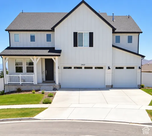Two-story residence featuring board-and-batten siding, a covered front porch with decorative brackets, a three-car garage, and dark-framed windows