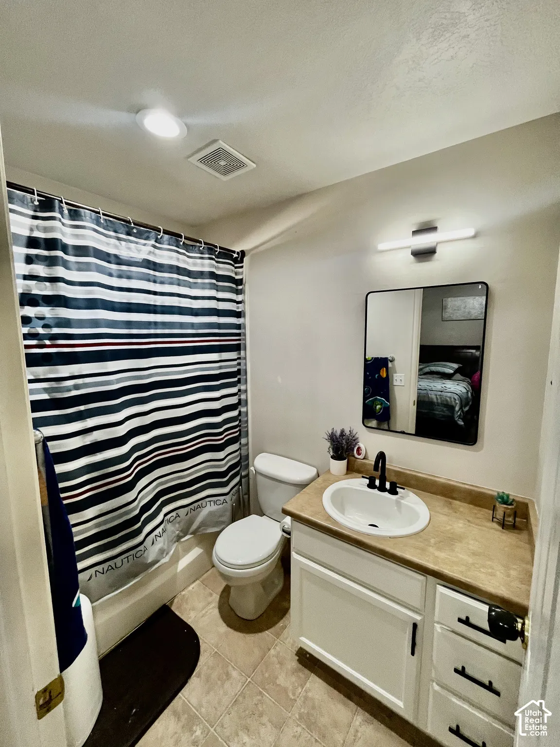 Bathroom featuring a white vanity cabinet with matte black hardware, integrated sink, stone-finish countertop, rectangular vanity mirror, and recessed lighting