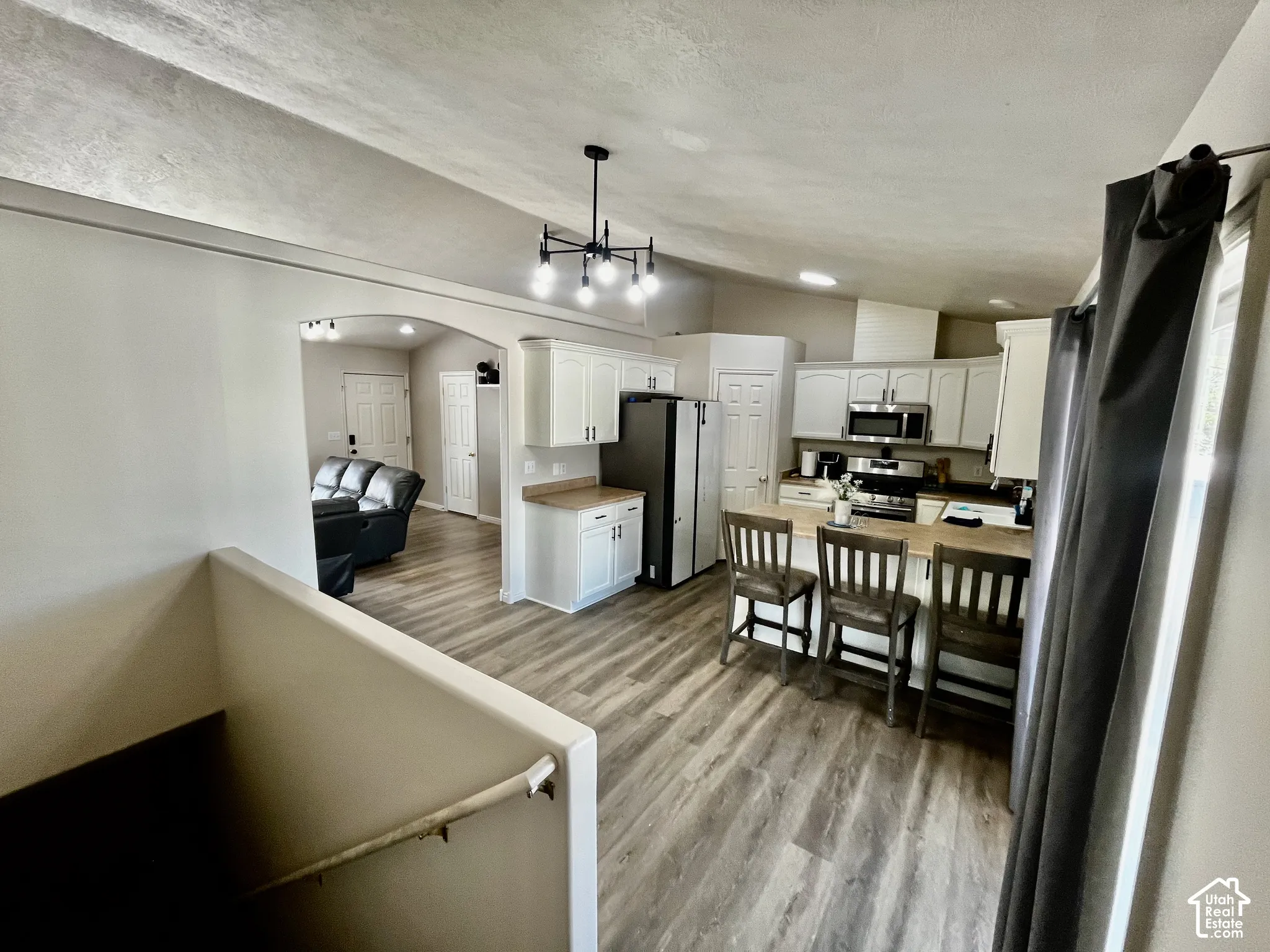 Kitchen featuring white cabinetry, wood-finish flooring, a breakfast bar, and a multi-arm chandelier