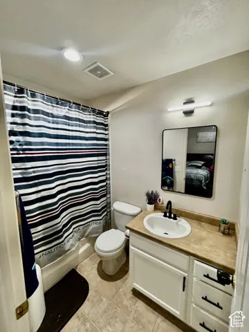 Bathroom featuring a white vanity cabinet with matte black hardware, integrated sink, stone-finish countertop, rectangular vanity mirror, and recessed lighting