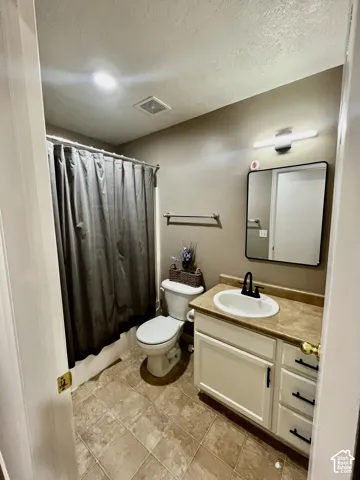 Bathroom featuring white cabinetry, solid-surface countertop with an integrated oval sink, matte black faucet hardware, square mirror with black frame, and tiled flooring