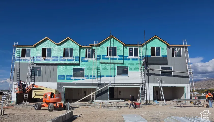 Multi-unit residential construction featuring vertical siding, multiple gabled rooflines, and ground-level garage bays