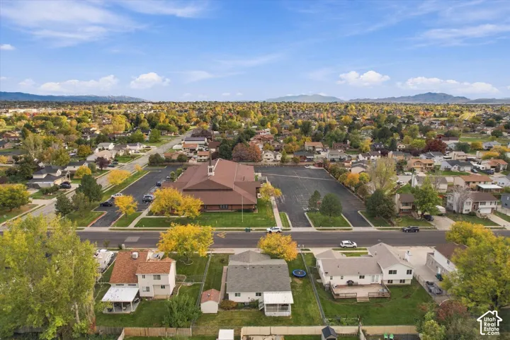 Aerial perspective of a residential neighborhood featuring mature trees and mountain range backdrop
