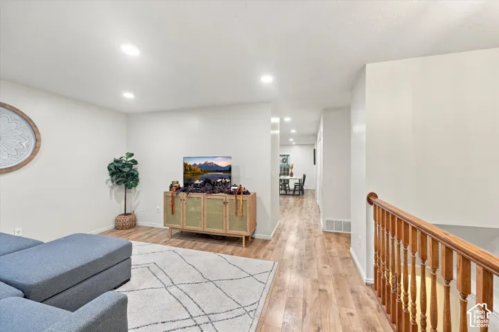 Wood-finish flooring, recessed lighting, and a wood-spindle stair railing