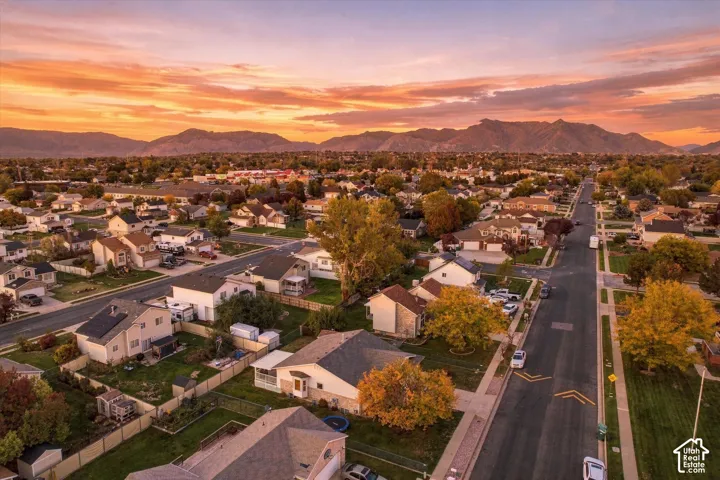 Aerial perspective featuring residential properties, mature trees, and a mountain range backdrop