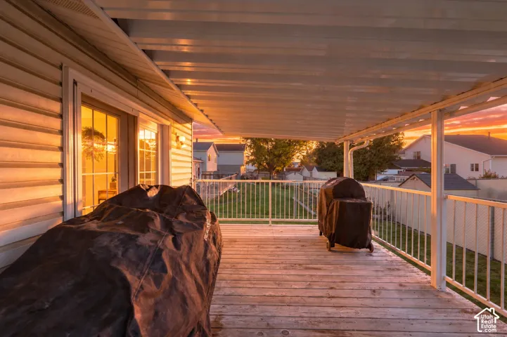 Covered wooden deck featuring a metal patio roof, horizontal siding, and white metal railings