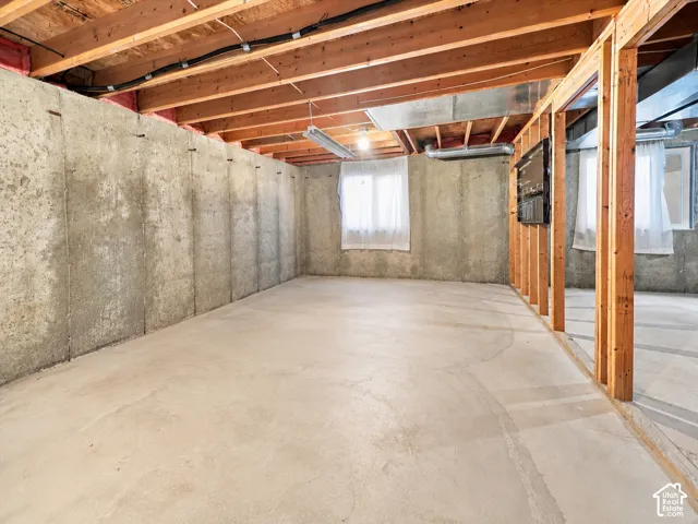 Unfinished lower level featuring concrete foundation walls, exposed wood-frame ceiling joists, concrete flooring, and multiple window openings