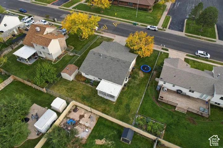 Aerial perspective featuring a landscaped backyard, a detached storage shed, a covered patio structure, and perimeter fencing