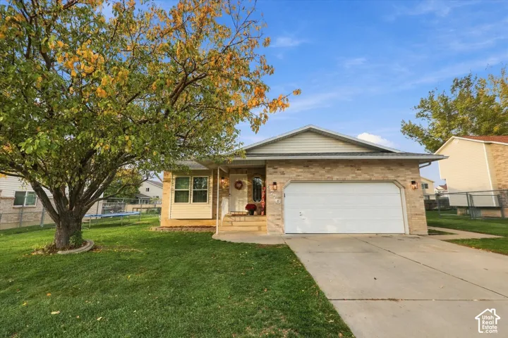 Split-level exterior featuring light brick masonry, horizontal siding, a concrete driveway, an attached two-car garage, and mature landscaping