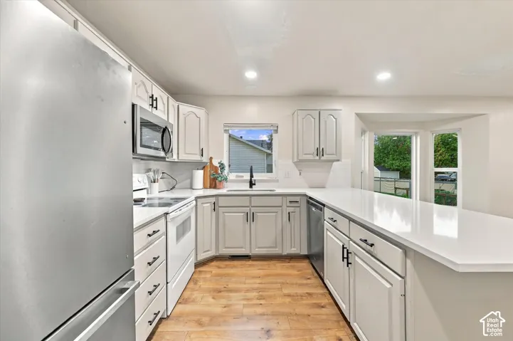 Kitchen featuring light-toned cabinetry, quartz countertops, wood-finish flooring, stainless steel appliances, and recessed lighting