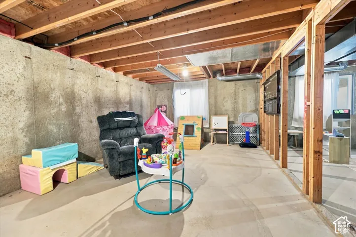 Unfinished lower level featuring exposed joist ceilings, poured concrete foundation walls, and concrete flooring