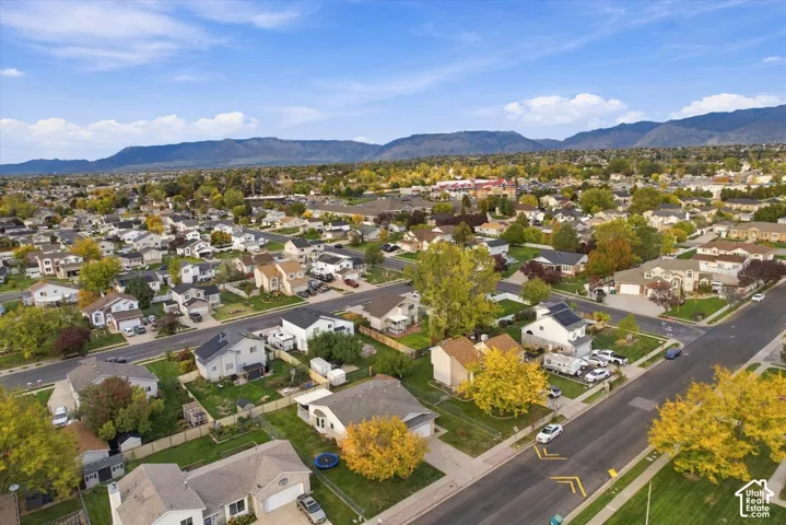 Aerial perspective of a residential neighborhood featuring paved streets, established tree canopy, and a prominent mountain range backdrop
