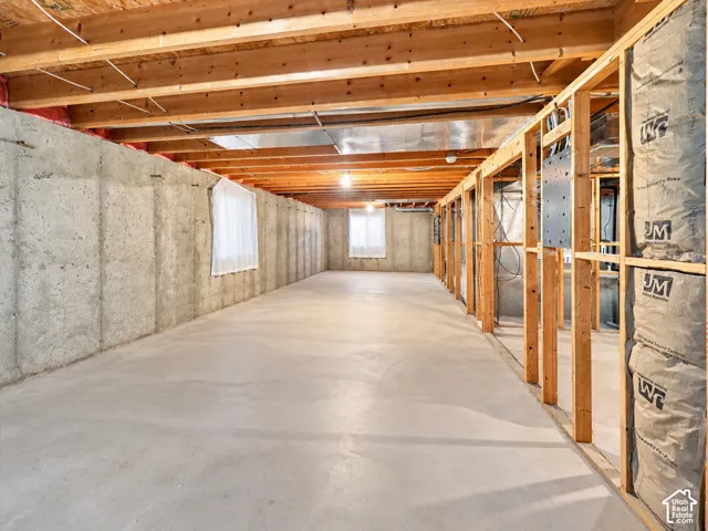 Unfinished basement featuring exposed wood-joist ceiling, poured concrete walls, and concrete flooring