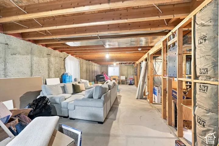 Unfinished lower level featuring exposed wood joists, concrete foundation walls, concrete flooring, and insulated wall framing