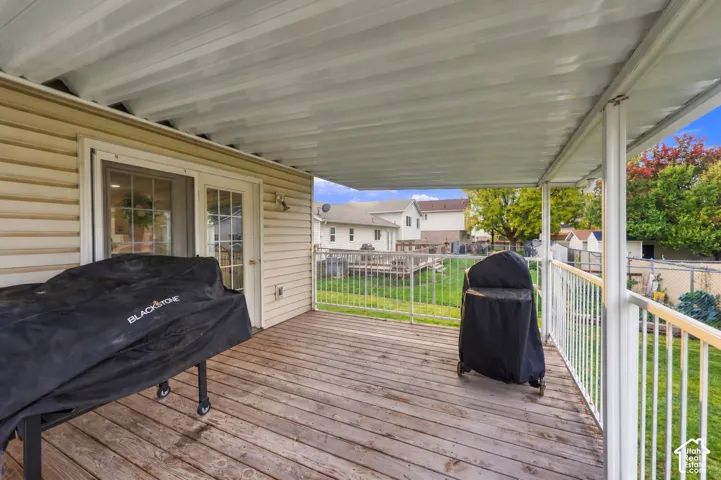 Covered deck featuring wood-plank flooring, metal railings, and vinyl siding