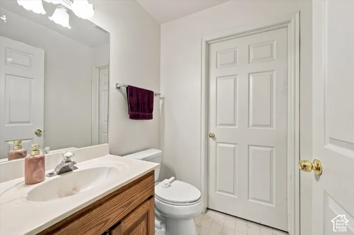 Wood-finish vanity cabinet, integrated countertop with oval basin, polished metal faucet, wall-mounted mirror, and multi-panel interior door