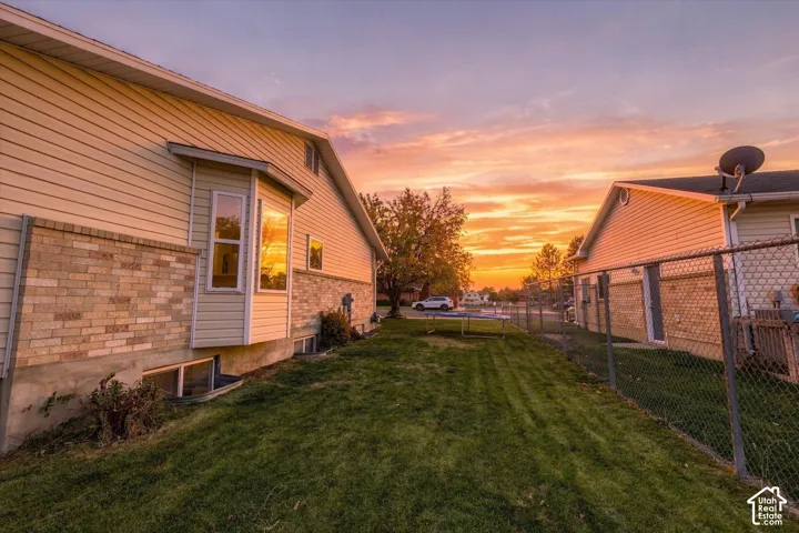 Exterior featuring vinyl siding, stone veneer accents, bay window, and chain-link fencing