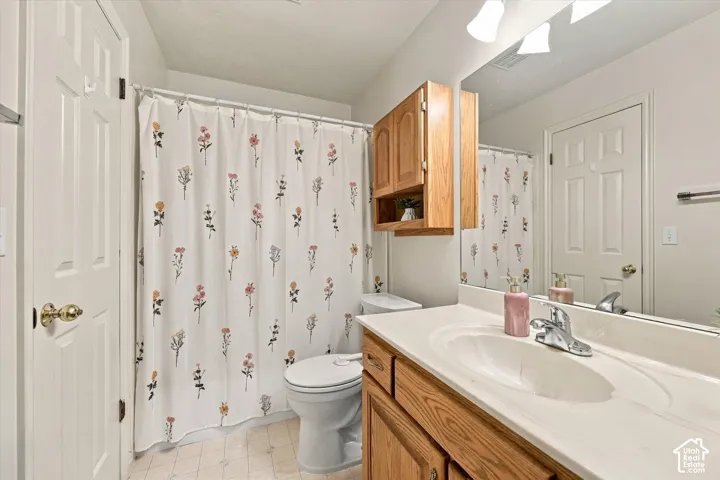 Bathroom featuring a wood vanity with a molded countertop and integrated basin, wall-mounted wooden cabinetry, a large vanity mirror, and a shower-tub combination