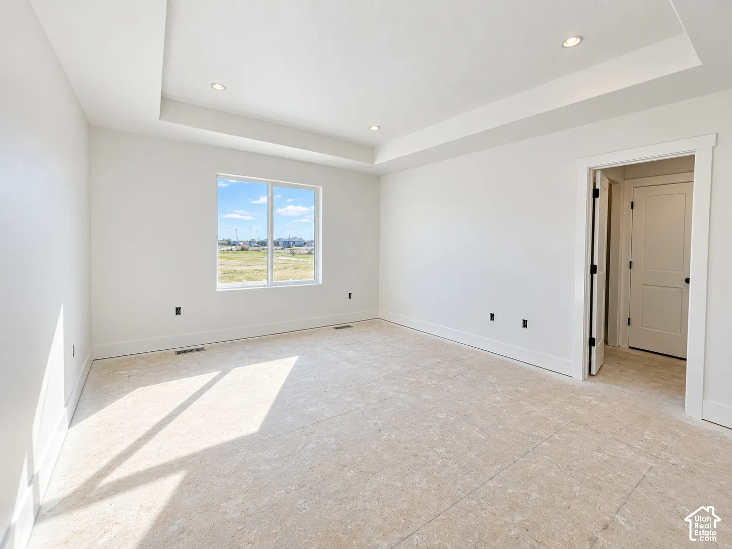 Interior space featuring a recessed tray ceiling, recessed lighting, and a single-pane window