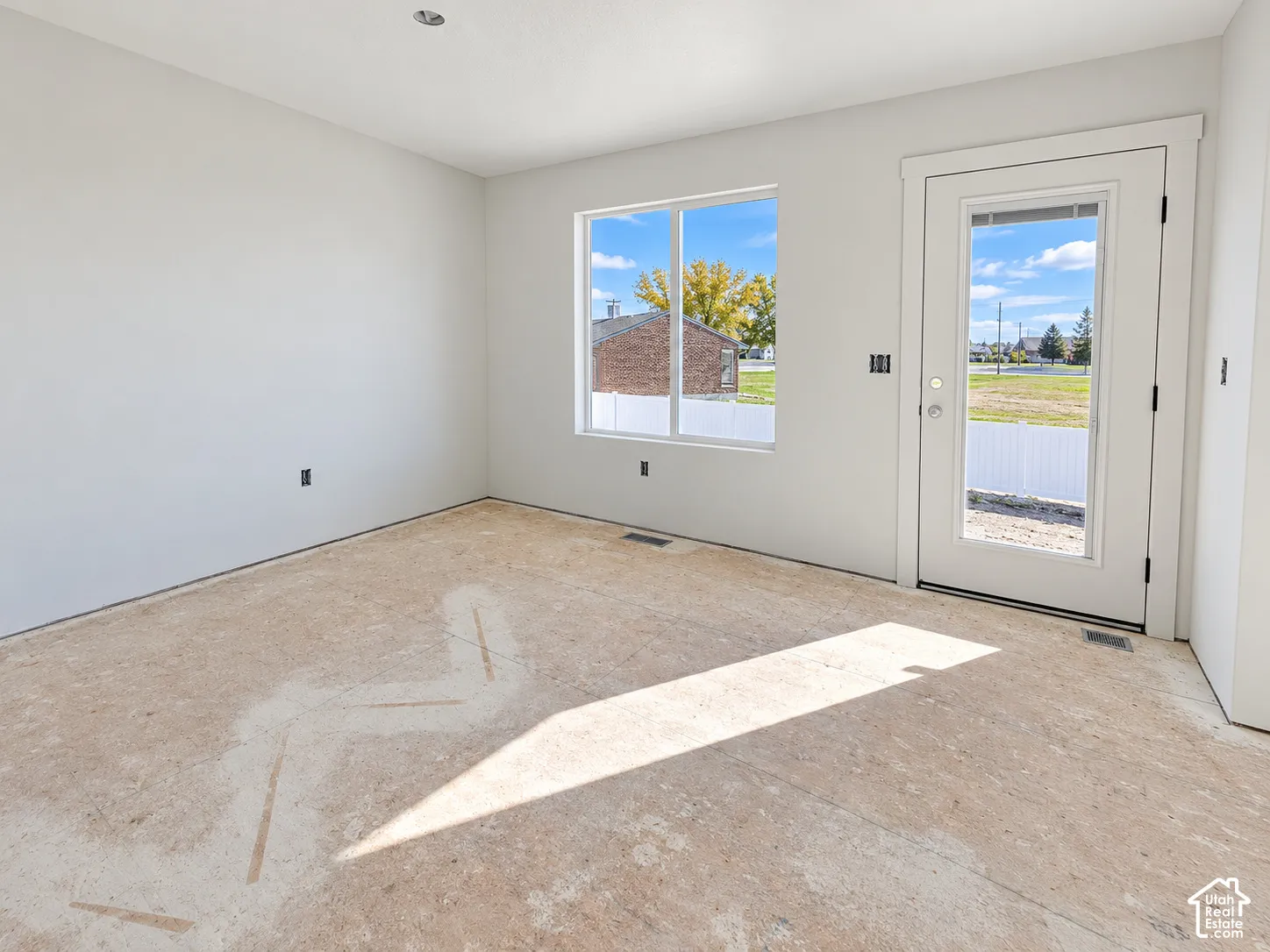 Neutral-toned interior space featuring a sliding window, a single-lite exterior door with a glass pane, recessed ceiling lighting, and smooth-finish wall surfaces