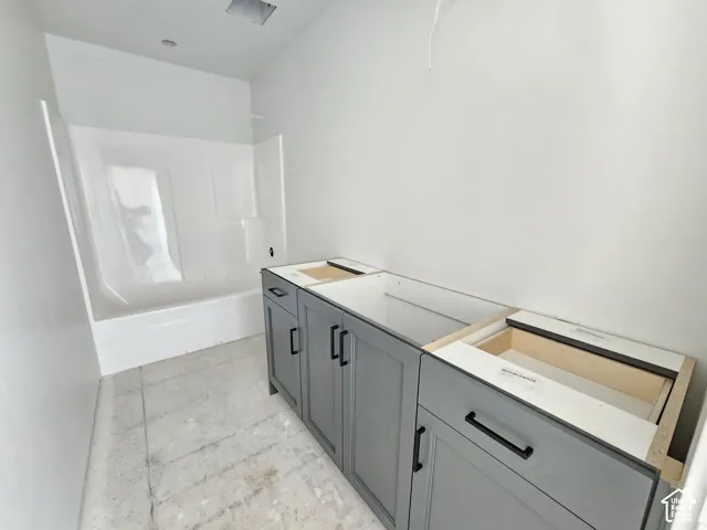 Shaker-style vanity cabinetry in slate gray with matte black hardware, accompanied by a white acrylic tub-and-shower surround