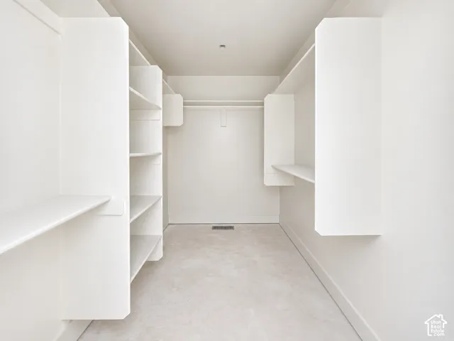 Walk-in closet featuring white built-in shelving, integrated hanging rods, and neutral carpeting