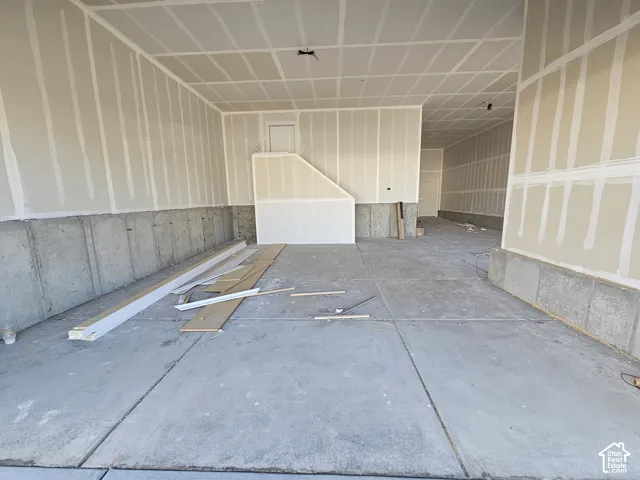 Multi-car garage space featuring concrete flooring, interior walls with unfinished drywall, and exposed concrete foundation walls