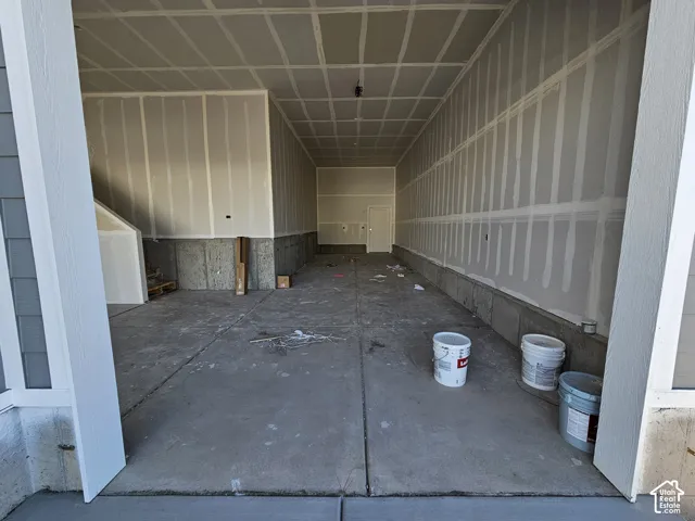Multi-car garage featuring a concrete slab floor, exposed gypsum board walls, and a dedicated service door