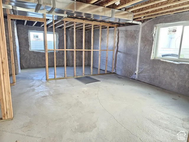 Unfinished space featuring concrete flooring, exposed wood framing, foundation walls with insulation, and multiple windows