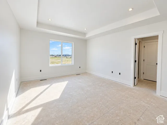 Interior space featuring a recessed tray ceiling, recessed lighting, and a single-pane window