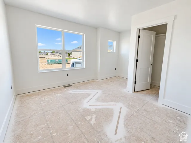 Interior space featuring crisp white walls, large double-pane windows, natural lighting, and a walk-in closet with a solid-core panel door