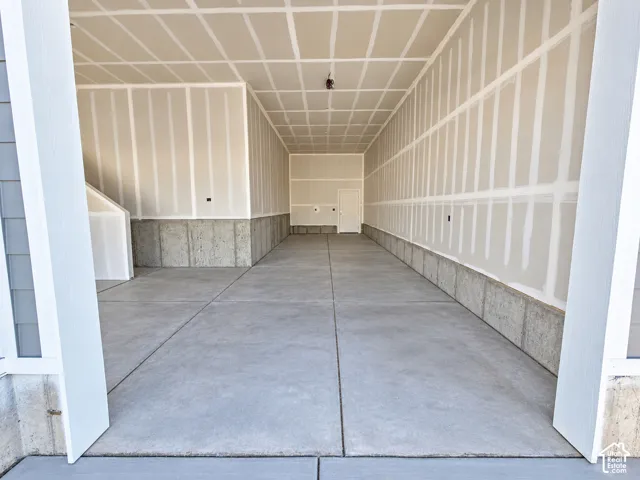 Spacious multi-car garage featuring a smooth concrete floor, finished drywall, concrete foundation walls, and a single-entry pedestrian door