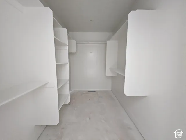 Walk-in storage space featuring built-in white shelving units and integrated clothing rods