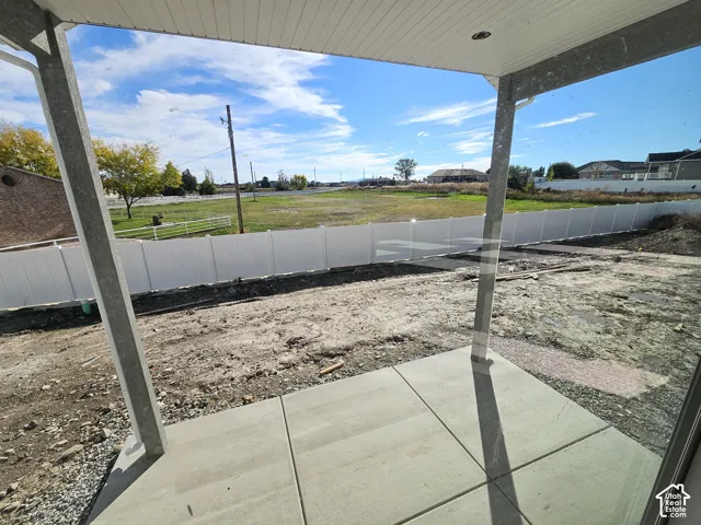 Covered concrete patio featuring recessed lighting and a full-height white vinyl privacy fence