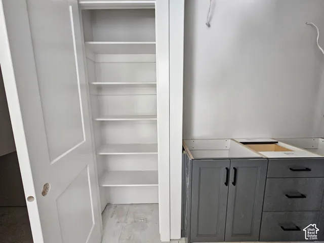 Built-in pantry featuring white shelving, paired with dark gray cabinetry highlighted by matte black hardware