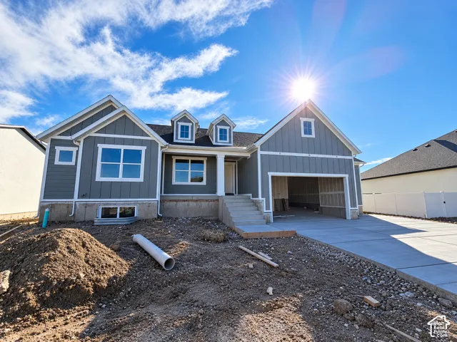 Board and batten siding exterior featuring two gable dormers, a concrete driveway, and an attached two-car garage