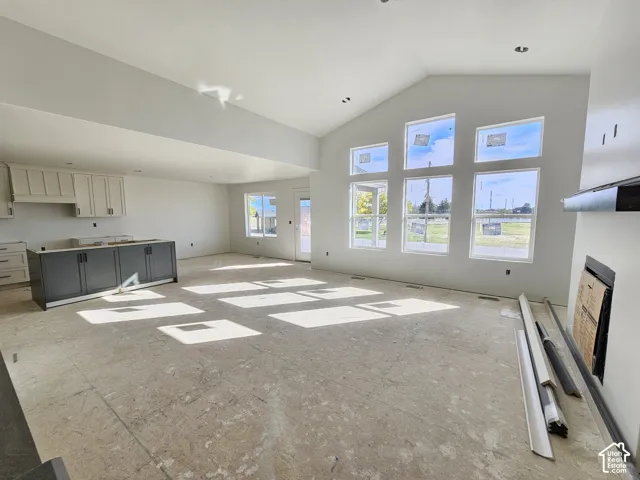 Vaulted ceilings, expansive multi-pane windows, built-in fireplace, and custom cabinetry featuring a contrasting island finish