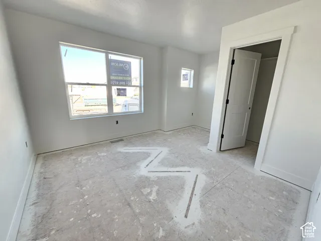 Neutral-toned room featuring a large dual-pane window, square accent window, interior shaker-style door, and crisp white wall trim