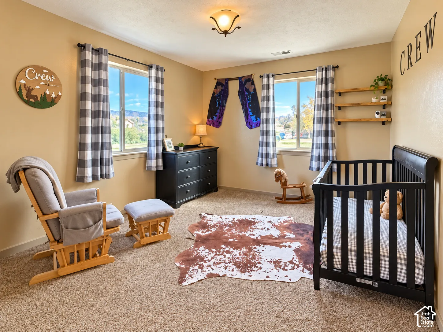 Bedroom featuring wall-to-wall carpeting, dual windows with natural lighting, and three tiered wall-mounted wooden shelves