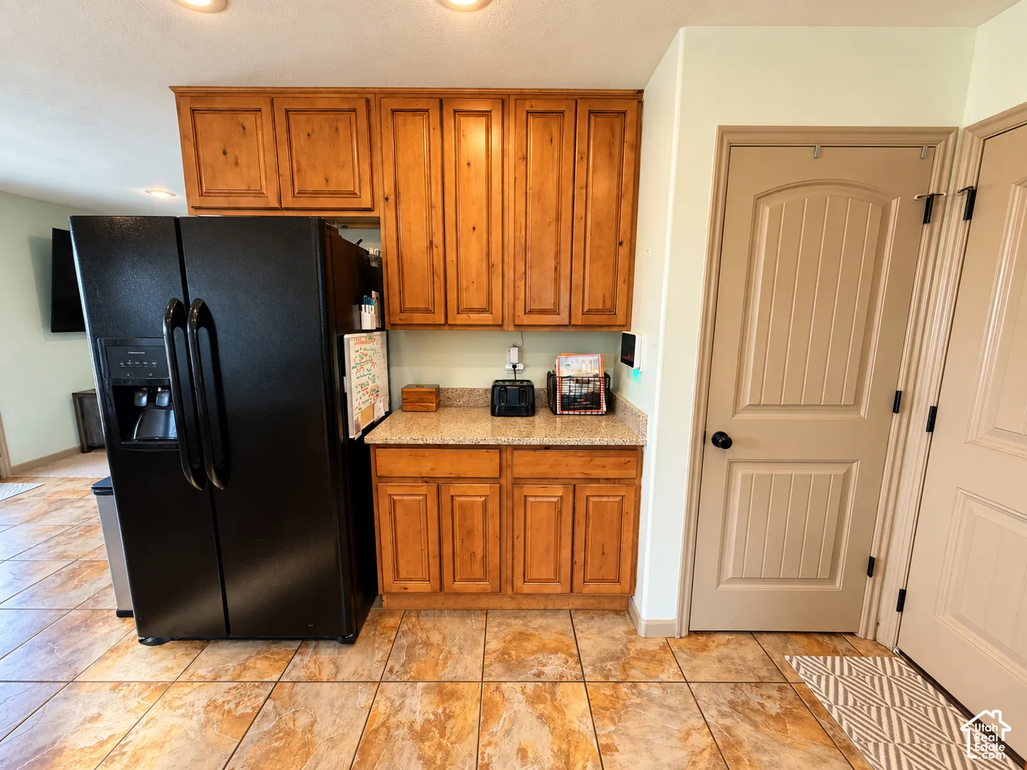 Natural wood-finish cabinetry featuring upper and lower storage, complemented by stone-finish countertops and tile flooring
