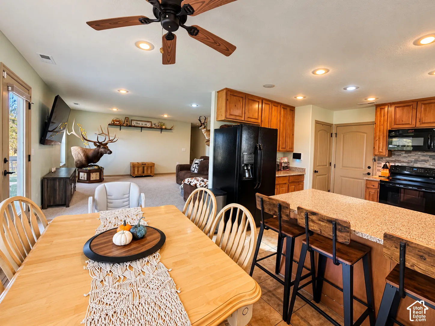 Kitchen featuring a large central island with a speckled countertop, custom wood cabinetry, recessed lighting, and tile flooring