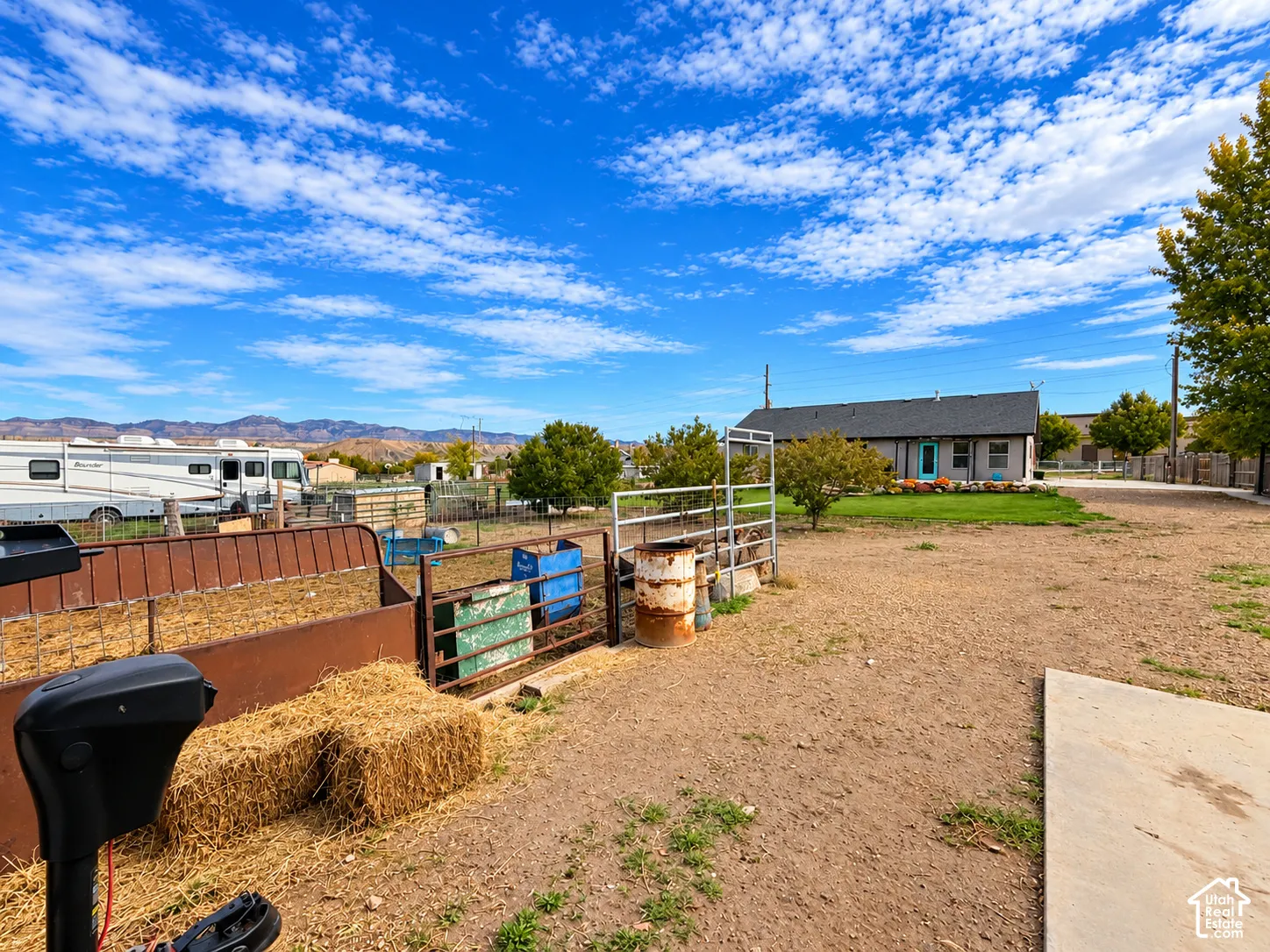 Expansive grounds featuring a metal perimeter fence, concrete apron, and mountain backdrop