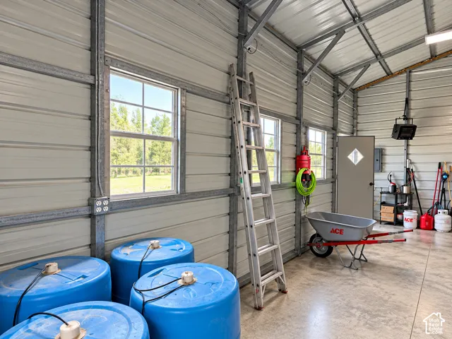 Metal-frame structure featuring exposed steel beams, corrugated metal wall panels, concrete flooring, and multiple grid-pattern windows